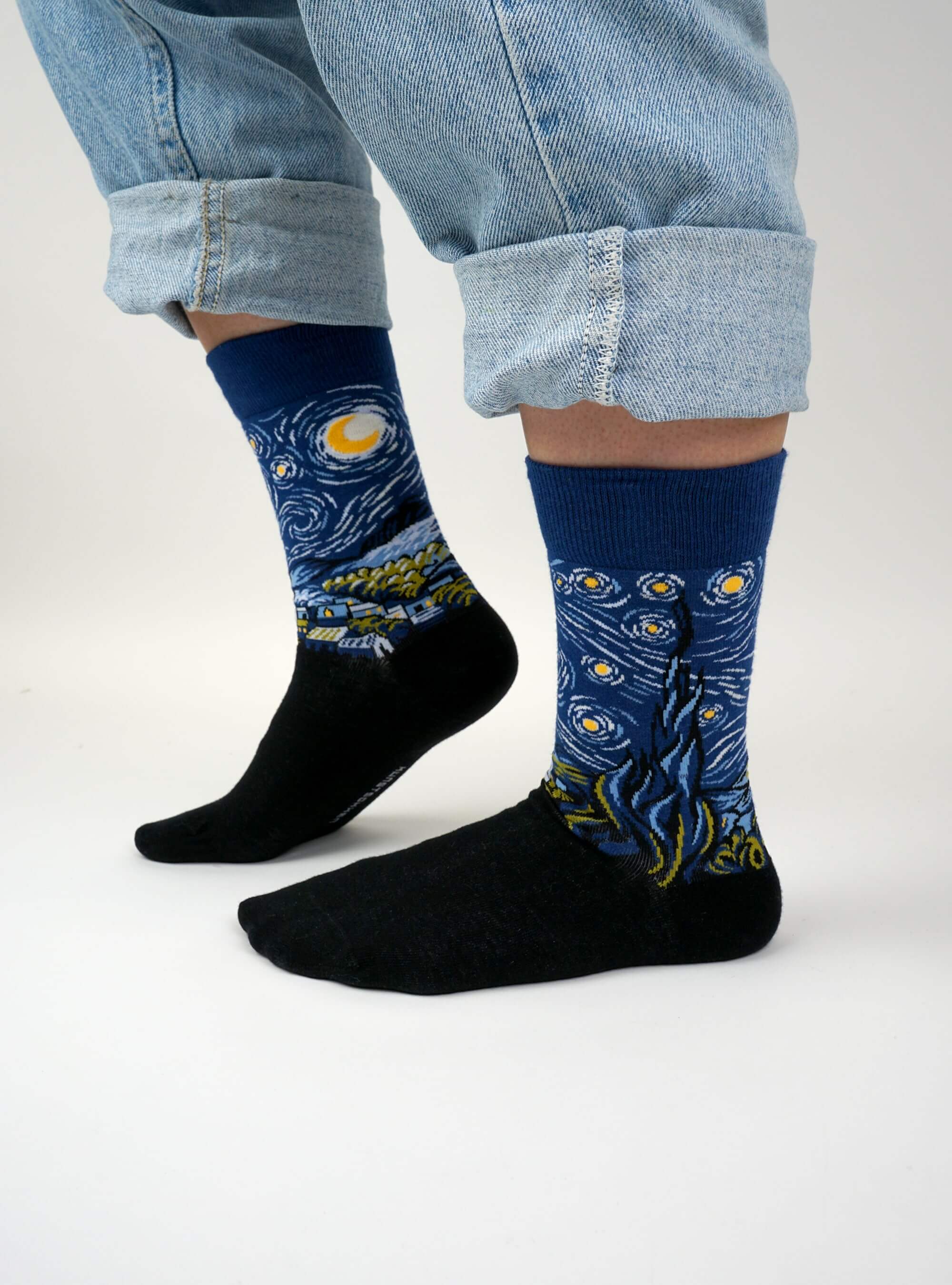 Persoon met opgerolde jeans draagt De Sterrennacht Sokken, met Van Gogh patroon